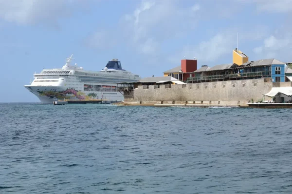 A cruise ship docked near colorful buildings and historic fortifications by the serene waters of Willemstad, Curaçao.