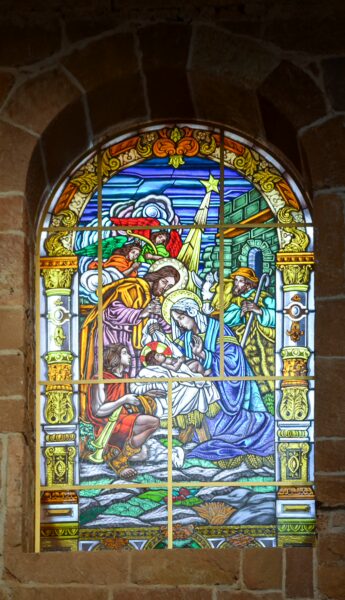 Vibrant stained glass window depicting the nativity scene in Barichara, featuring detailed figures and colorful designs.
