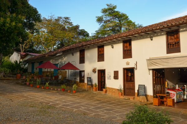 Charming colonial architecture with wooden balconies and terracotta roofs, surrounded by lush greenery in Barichara, Colombia.