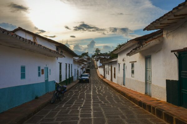 Charming cobblestone street in Barichara, Colombia, lined with whitewashed houses and a warm sunset in the background.