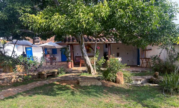 Charming courtyard in Barichara, Colombia, featuring lush greenery, rustic stone pathways, and traditional whitewashed buildings.