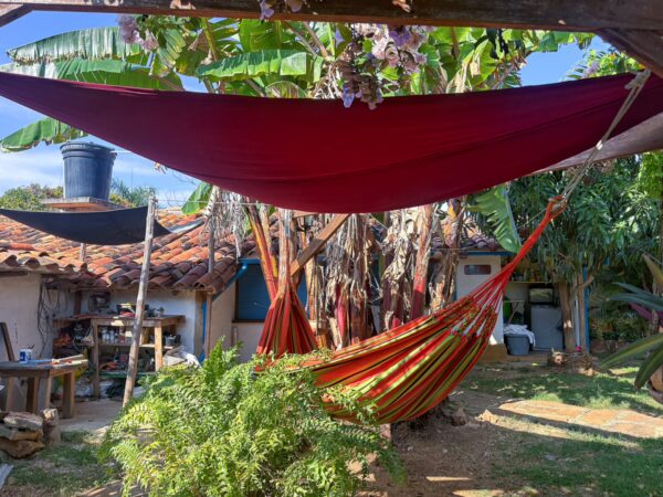 Colorful hammocks hang between trees in a peaceful garden in Barichara, Santander, Colombia, surrounded by lush greenery.