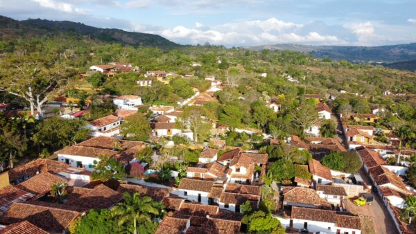 Aerial view of Barichara, Colombia, showcasing traditional red-tiled roofs, lush greenery, and winding cobblestone streets.