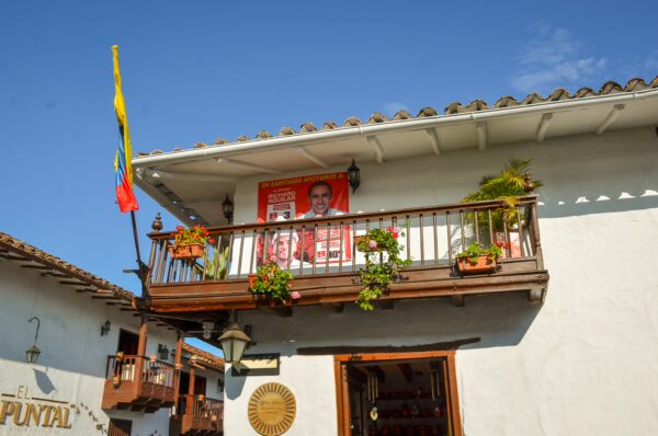 Colorful balcony adorned with plants and flags, featuring a prominent banner in the charming streets of Barichara, Santander, Colombia.