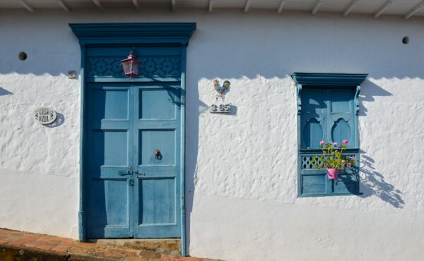 Charming blue door and window with floral details on a whitewashed building in Barichara, Santander, Colombia.