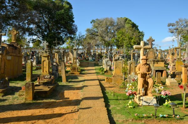 Barichara cemetery with stone tombs, crosses, and a central path under tall trees and a blue sky