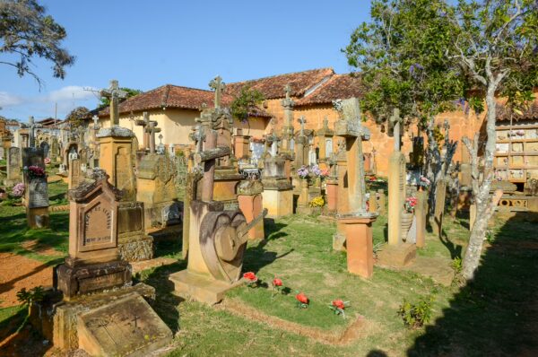 Graves adorned with flowers in the scenic cemetery of Barichara, surrounded by lush greenery and traditional architecture.