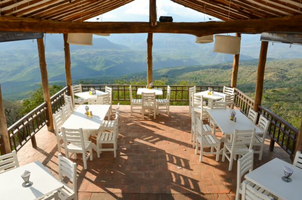 Open-air terrace with white tables and chairs overlooking the hills and valleys near Barichara, Colombia
