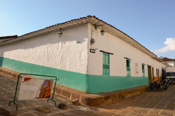 Whitewashed building with green accents in Barichara, Santander, Colombia, showcasing traditional architecture against a blue sky.