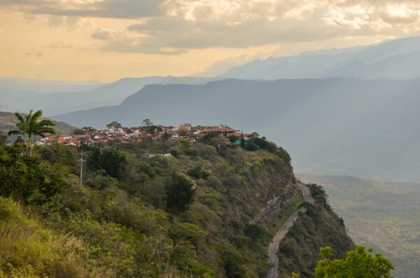 Stunning view of Barichara, Colombia, perched on a cliff with rolling hills and a soft sunset glow illuminating the landscape.