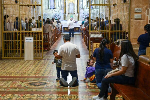 Inside the Cathedral of the Immaculate Conception in Barichara, people sit and stand along the aisle during a service or rehearsal