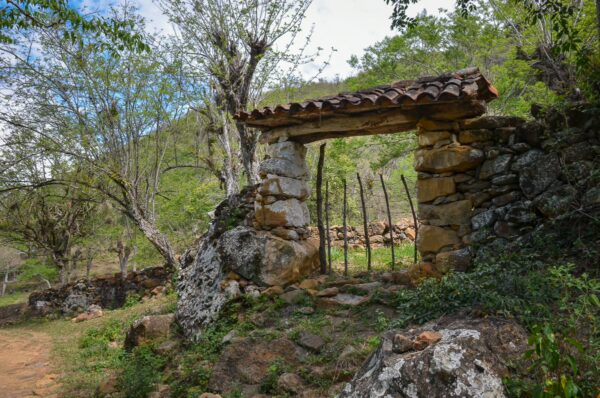 Stone gateway on the Camino Real trail near Barichara, with dry forest, rocks, and a dirt path in Santander, Colombia