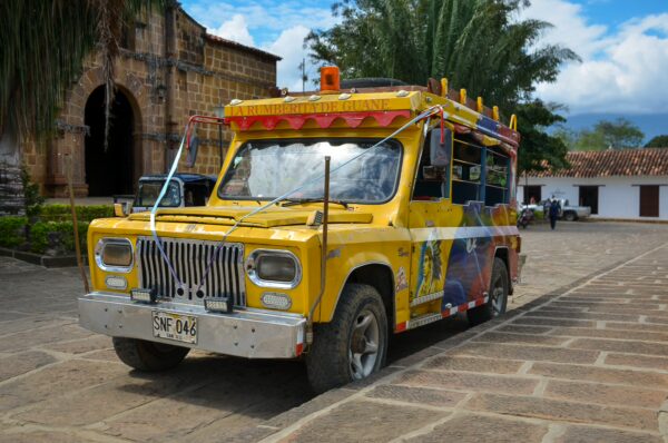 Colorful jeep parked on cobblestone street in Guane, Santander, Colombia, with traditional architecture in the background.