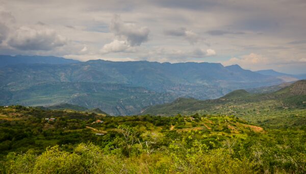 Rolling green hills and distant mountains under a cloudy sky near Guane, Villanueva, Santander, Colombia.