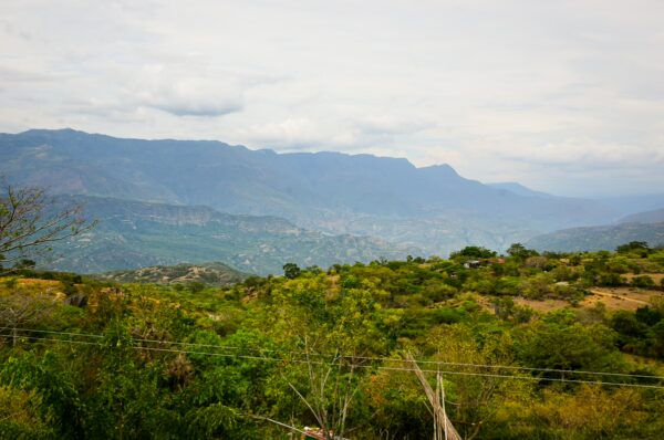 Rolling green hills with a backdrop of misty mountains in Guane, Santander, showcasing Colombia's natural beauty.