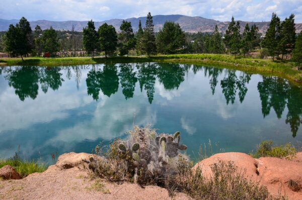 Blue lake reflecting trees and mountains at Pozos Azules, Villa de Leyva, Boyacá, Colombia