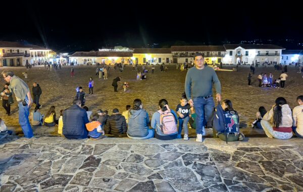 Visitors gather in the lively square of Villa de Leyva at night, illuminated buildings creating a vibrant atmosphere.