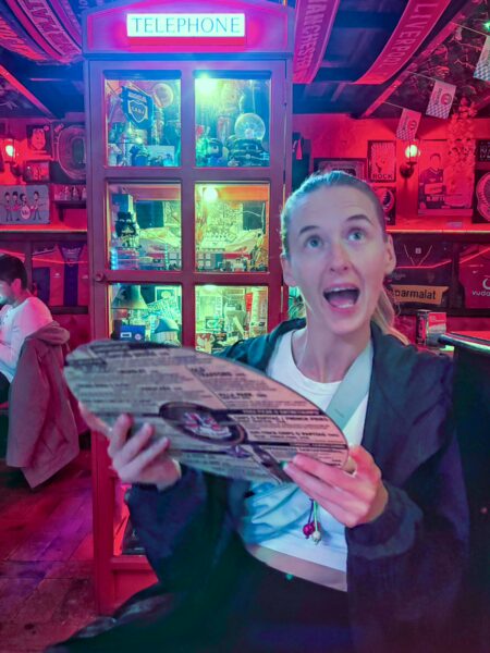 Woman holding a vinyl-shaped menu inside the colorful interior of Chelsea Pub in Villa de Leyva, Boyacá, Colombia