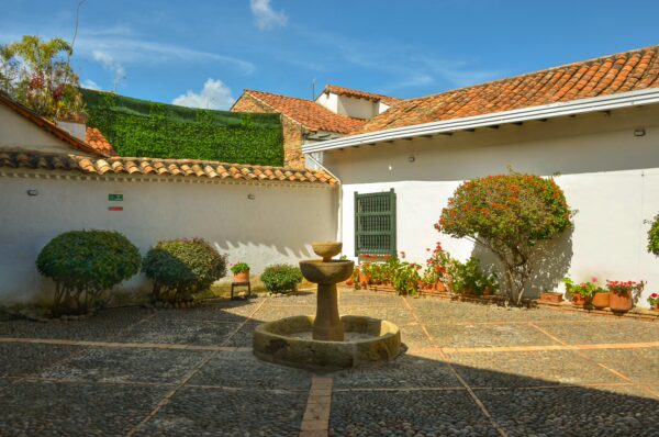 Colonial courtyard with a stone fountain and potted flowers at Casa Museo Antonio Nariño in Villa de Leyva, Boyacá, Colombia