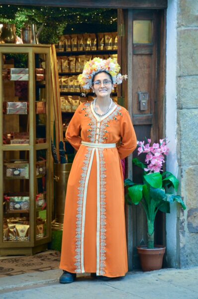 Woman in traditional orange dress standing outside a handicrafts shop in Villa de Leyva, Boyacá, Colombia
