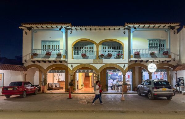 Two-story colonial building with arched balconies and flower-filled window boxes along Carrera 13 in Villa de Leyva, Boyacá, Colombia