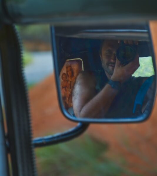 Reflective view in a side mirror, showing a photographer capturing scenic landscapes in Villanueva, Santander, Colombia.