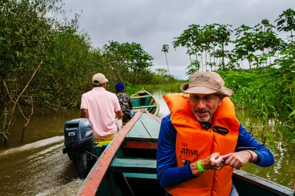 Travelers navigate a narrow waterway, wearing life jackets, surrounded by lush greenery in Gamboa Nature Reserve, Loreto, Peru.