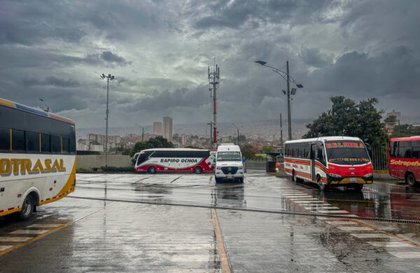 Buses parked at Terminal del Norte in Medellín, Antioquia, with a rain-soaked pavement and dramatic overcast skies.