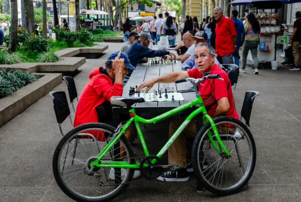 Men play chess at Plazuela San Ignacio in Medellín, with a bright green bicycle in the foreground