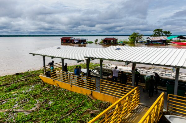 Visitors enjoy the scenic view from a dock in Puerto Narino, Amazonas, Colombia, surrounded by lush greenery and calm waters.