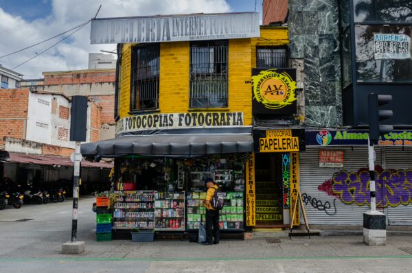 Bright yellow photocopy shop with a variety of newspapers and magazines, located on a bustling street in Medellín, Colombia.