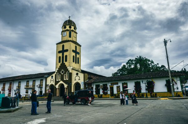 Vibrant Plaza Bolívar in Salento, Quindío, features a striking clock tower surrounded by colorful buildings and visitors enjoying the scenery.