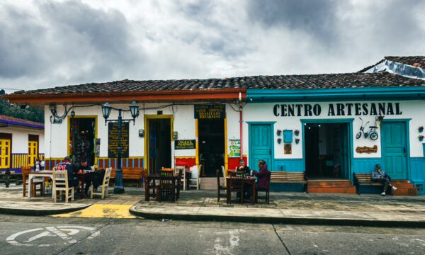 Colorful shops line the street at Plaza Bolívar in Salento, Quindío, showcasing local crafts and inviting outdoor seating.