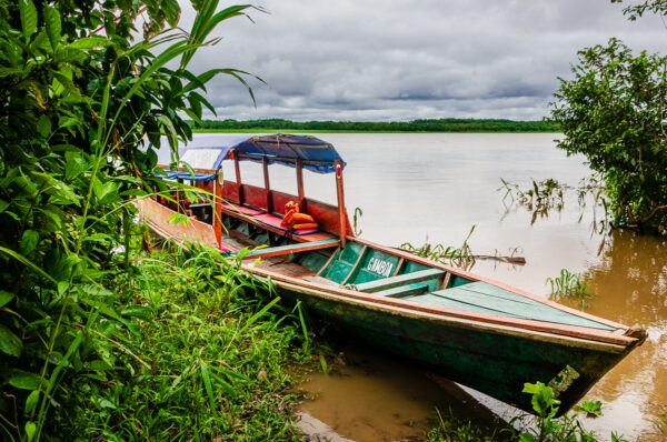 Colorful boat resting on the muddy banks of the Gamboa Nature Reserve, surrounded by lush greenery in Loreto, Peru.