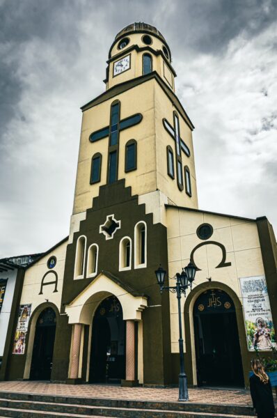 Nuestra Señora de Carmen features a striking church facade with large crosses and a clock tower against a moody sky in Salento, Quindío.