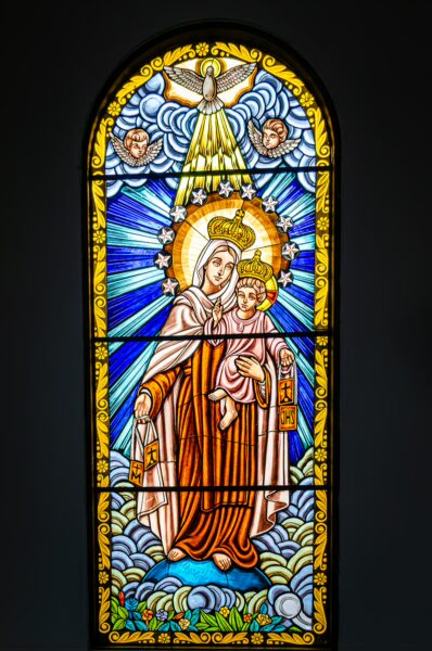 Stained glass window depicting Nuestra Señora de Carmen, vibrant colors and intricate details in Salento, Quindío, Colombia.