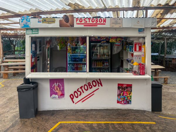 Colorful snack kiosk featuring a variety of drinks and snacks, with a Postobón sign prominently displayed at Arví Park, Medellín.