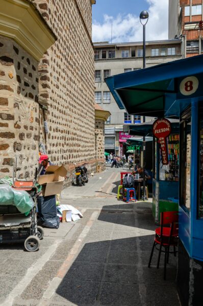 Narrow alley in Medellín, showcasing colorful stalls and brick buildings under a bright sky.