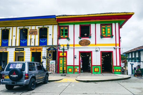 Colorful colonial buildings with vibrant facades and decorative windows line the streets of Plaza Bolívar in Salento, Quindío, Colombia.