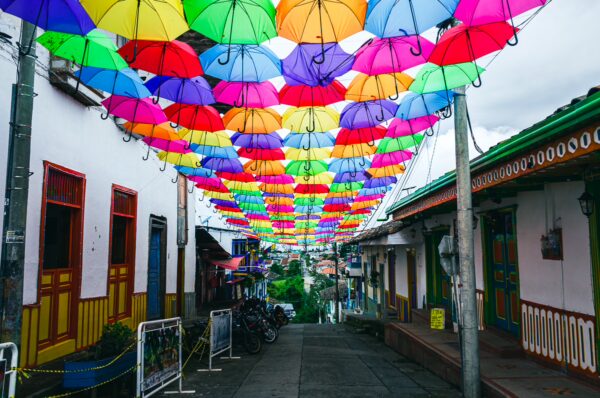 Colorful umbrellas create a vibrant canopy over Calle Real, enhancing the charm of Salento, Quindío, Colombia.