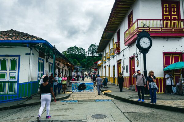 Colorful houses line Calle Real in Salento, Quindío, Colombia, bustling with people and featuring a striking clock.