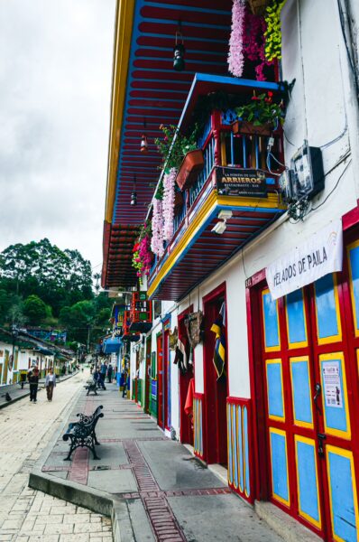 Vibrant calle Real in Salento features colorful buildings adorned with flowers and local artisan shops lining the cobblestone street.
