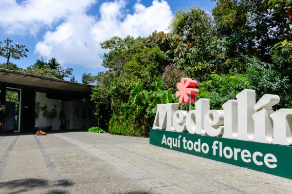Colorful entrance sign of Medellín, surrounded by lush greenery in Arví Park, inviting visitors to explore the vibrant nature.