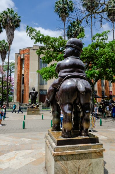 Botero bronze sculpture of Sancho Panca in Plaza Botero, Medellín, with Museo de Antioquia and passersby in the background