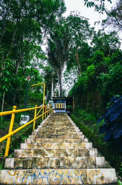 Colorful steps lead up to a small structure surrounded by lush greenery at Alto de la Cruz in Salento, Quindío, Colombia.
