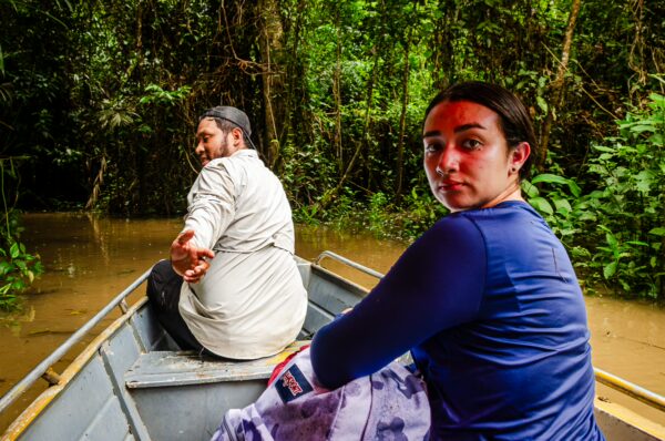 Exploring the lush greenery of Gamboa Nature Reserve in Loreto, Peru, two travelers navigate the tranquil waters in a small boat.