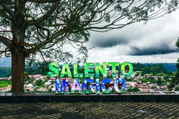 Colorful "Salento Magico" sign against a cloudy sky, overlooking the vibrant town of Salento in Quindío, Colombia.