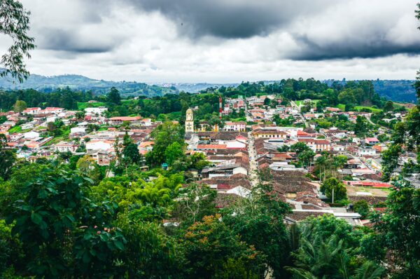 Colorful houses and lush greenery characterize the view from Alto de la Cruz in Salento, Quindio, Colombia, under a cloudy sky.