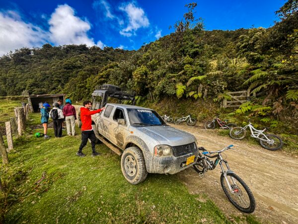 Adventurous travelers prepare for a ride with bikes and a dusty truck in the lush Carbonera Valley, Quindío, Colombia.