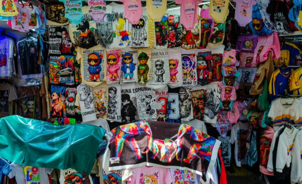 Vibrant display of colorful T-shirts and merchandise in Comuna 13, Medellín, showcasing local art and culture.
